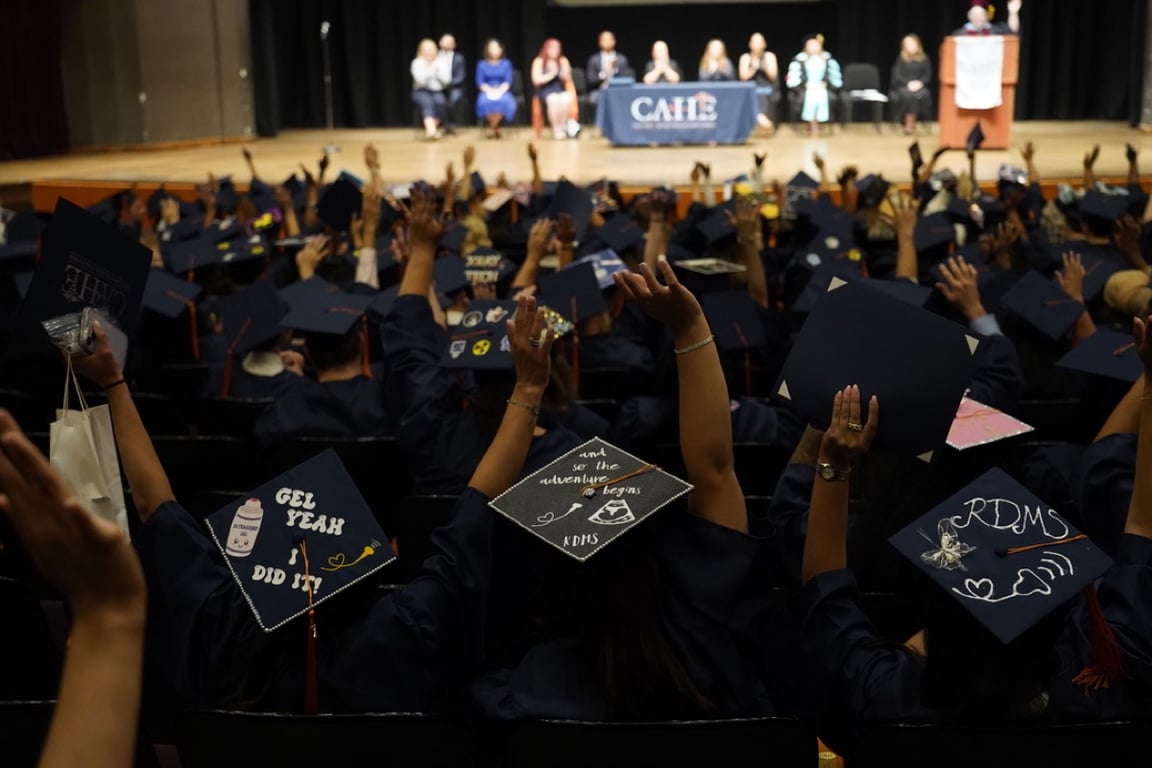 Graduates raising decorated caps at the CAHE commencement ceremony